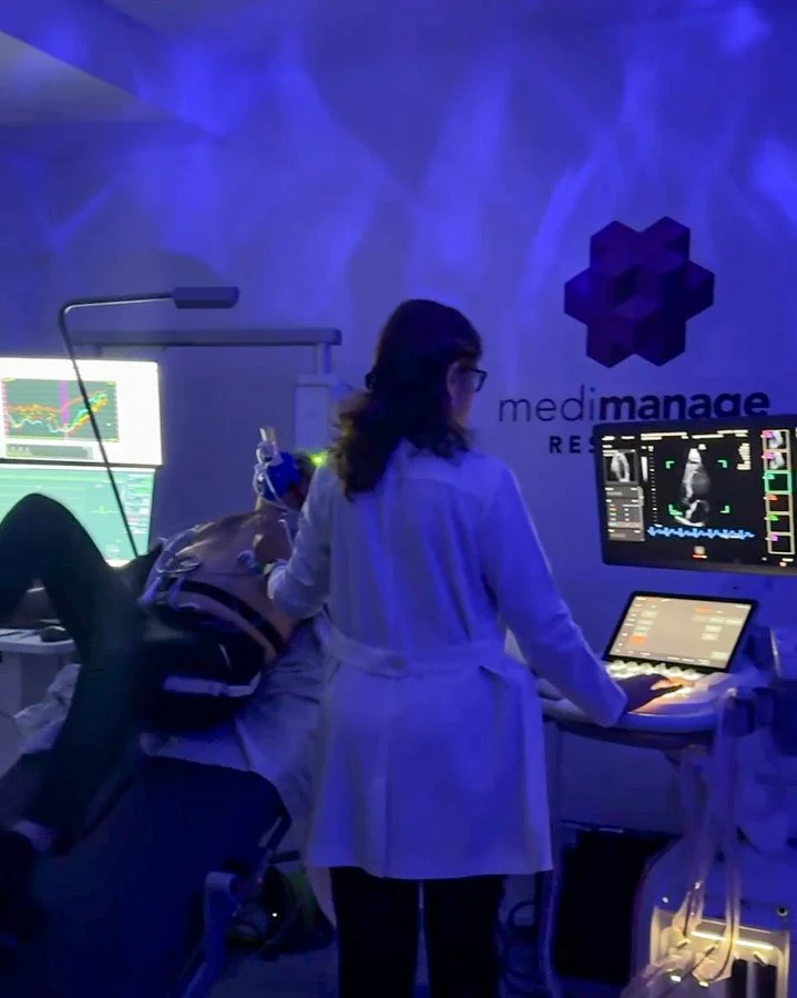 Ecocardiograma con Cicloergómetro en CDMX — paciente pedaleando con electrodos y especialista tomando imágenes ecográficas en Medimanage Research